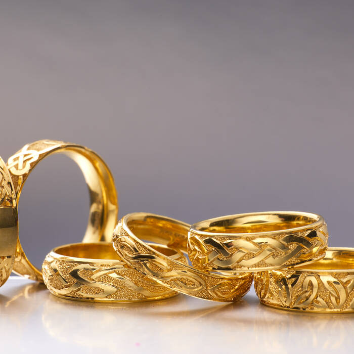 A selection of seven artisanal gold rings featuring intricate Celtic knotwork, braided patterns, and textured finishes, showcasing traditional Welsh jewellery design.