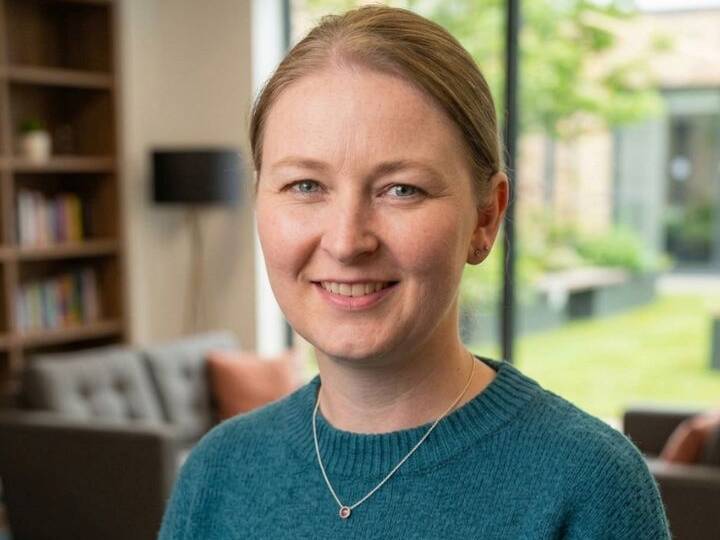Headshot of Kelly, Operations director at Welsh Gold, smiling in a bright, modern office setting wearing a teal sweater.