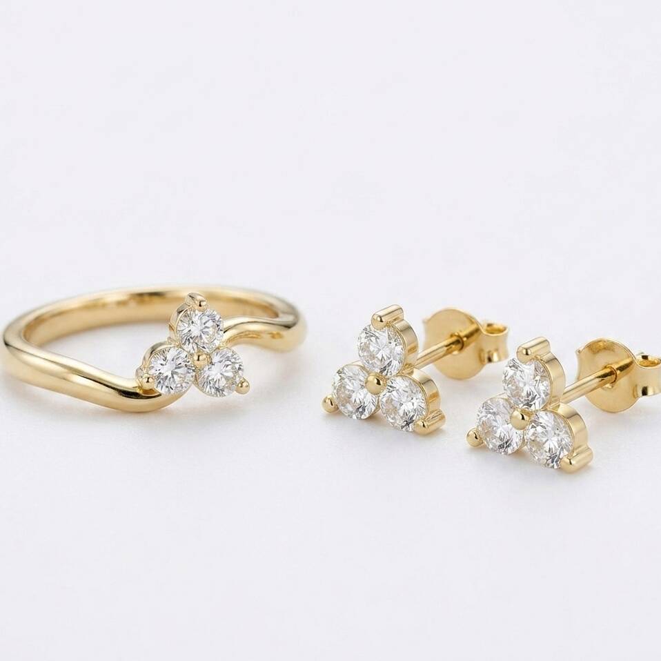 A matching jewellery set in solid Welsh gold, featuring a classic trilogy ring with three round brilliant-cut diamonds alongside a pair of coordinating diamond stud earrings.