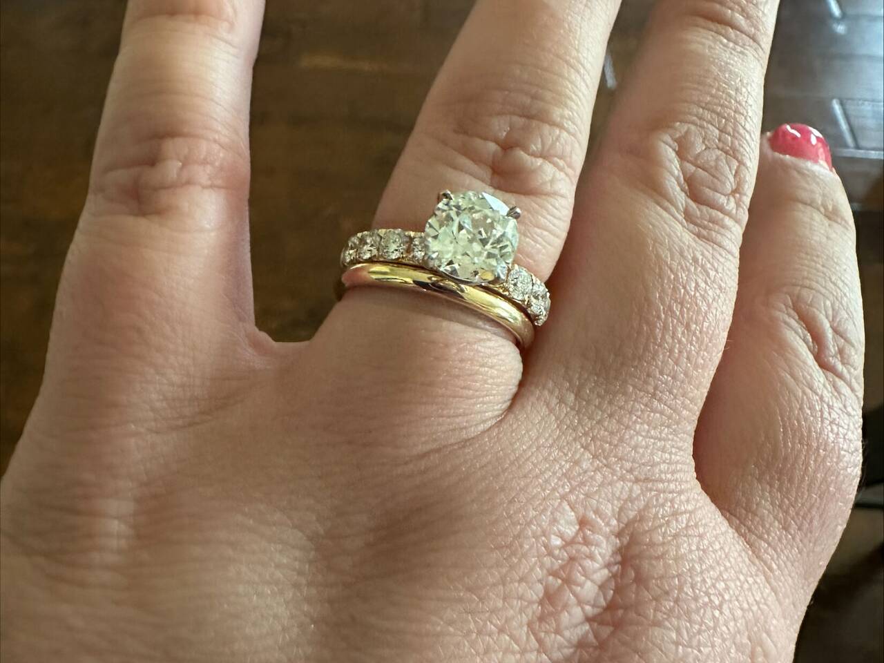 A customer wearing her new 100% Welsh gold wedding ring inset with one large central Diamond cushioned by a shoulder of Diamonds